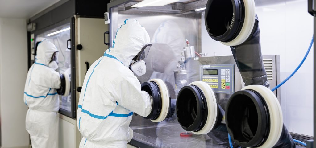 Scientist handling a high-potency active pharmaceutical ingredient in a contained CDMO laboratory